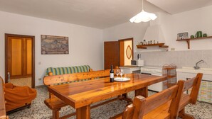 A dining area with a wooden table and benches, a kitchen with white appliances, and a map on the wall. - Holiday Home 'Poggio1' with Shared Pool, Shared Garden and Wi-Fi (Fauglia)