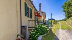 A house with a paved driveway, a small garden, and a metal railing. - Holiday Home 'Poggio1' with Shared Pool, Shared Garden and Wi-Fi (Fauglia)