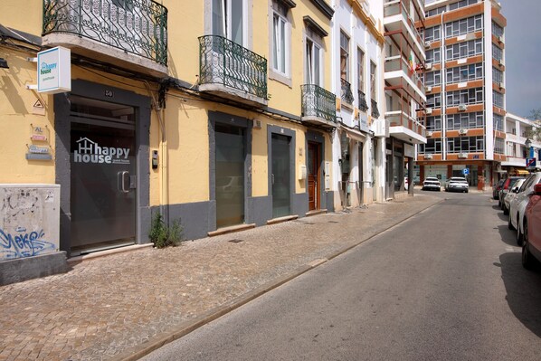 Un edificio con un letrero que dice 'Happy House', una calle empedrada y coches aparcados.