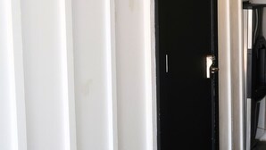 Eine schwarze Tür mit silbernem Griff, weißen Wänden und einem sichtbaren Türrahmen.