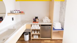 Eine kompakte Küchenzeile mit integriertem Kühlschrank, einer Spüle und einer Arbeitsplatte mit Stauraum.