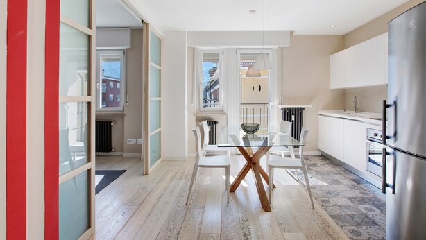 A modern kitchen with a glass dining table, white chairs, and a stainless steel refrigerator. - 'Surville' Apartment in Aosta with Mountain View and Balcony (Aosta)