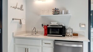 Een moderne keuken met witte kasten, een ingebouwde magnetron en een vaatwasser.