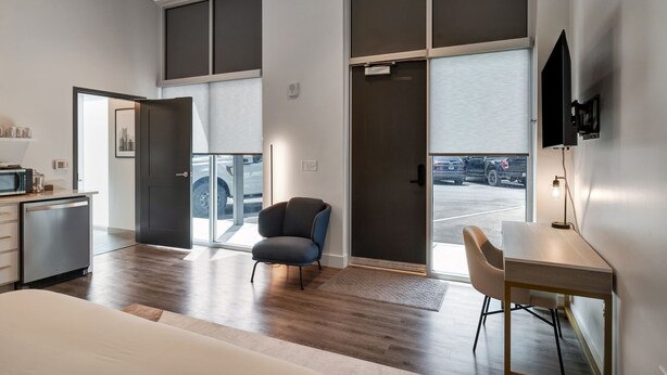 Een moderne hotelkamer met een groot raam, een bureau, een stoel en een bed.
