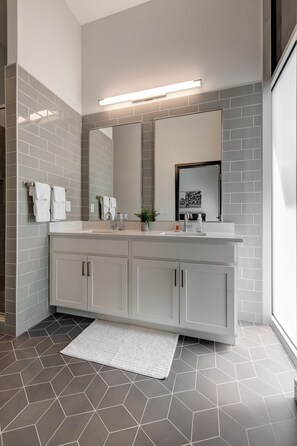 A modern bathroom with a large mirror, two sinks, and a white countertop. - Professional Retreat Double Queen Room (Nashville)