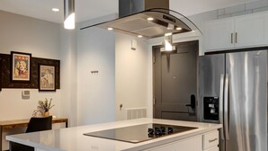 Een moderne keuken met een centraal kookeiland, roestvrijstalen apparatuur en witte kastjes.