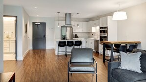 Una cocina moderna con armarios blancos, una campana de acero inoxidable y un comedor con mesa de madera y sillas negras.
