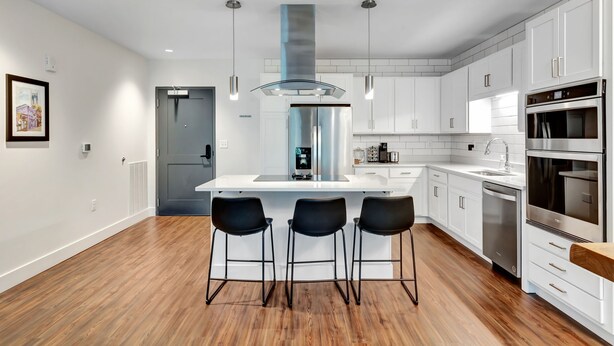 A modern kitchen with white cabinetry, stainless steel appliances, and a central island with bar stools. - Neon Nest: One Bedroom Nashville Getaway (Nashville)