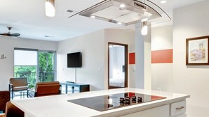 A modern kitchen with a central island, pendant lighting, and a large window. - Neon Nest: One Bedroom Nashville Getaway (Nashville)
