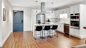 A modern kitchen with white cabinetry, stainless steel appliances, and a central island with bar stools.