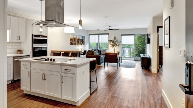 A modern kitchen with white cabinetry, a central island, and pendant lighting.