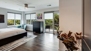 Een moderne slaapkamer met een groot bed, een dressoir en uitzicht op de omgeving door grote ramen.