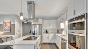 Une cuisine moderne avec des meubles blancs, des appareils électroménagers en acier inoxydable et un îlot central.