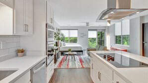 Une cuisine moderne avec des meubles blancs, un îlot central et une vue sur un balcon.