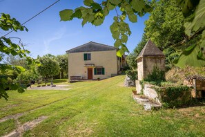 Une maison avec une pelouse devant, une petite tour et un banc.