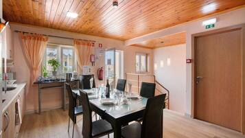 Un coin repas avec un plafond en bois, une table dressée pour quatre personnes et une porte portant un panneau indiquant la sortie de secours.