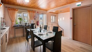 Un coin repas avec un plafond en bois, une table dressée pour quatre personnes et une porte portant un panneau indiquant la sortie de secours.