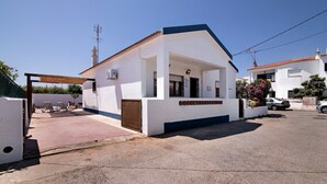 A white building with a blue roof, a covered entrance, and a small porch. - Holiday Home 'Casa Maria Beatriz' with Private Terrace, Private Garden and Wi-Fi (Vila Nova de Cacela)