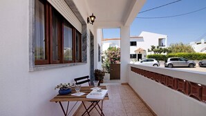 A balcony with a table, chairs, a potted plant, and a lamp. - Holiday Home 'Casa Maria Beatriz' with Private Terrace, Private Garden and Wi-Fi (Vila Nova de Cacela)
