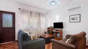 A living room with a sofa, a coffee table, a TV, and a bookshelf. - Holiday Home 'Casa Maria Beatriz' with Private Terrace, Private Garden and Wi-Fi (Vila Nova de Cacela)