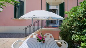 A balcony with a white table, two potted plants, and a white umbrella. - Holiday Home 'Villa Liberty Rosa' with Sea View, Wi-Fi and Air Conditioning (San Vincenzo)