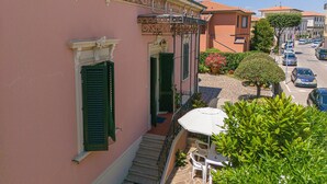 A pink building with a balcony, a staircase, and a small table with a white umbrella. - Holiday Home 'Villa Liberty Rosa' with Sea View, Wi-Fi and Air Conditioning (San Vincenzo)