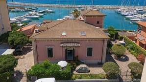 A building with a tiled roof, a covered car, and a view of a marina with boats. - Holiday Home 'Villa Liberty Rosa' with Sea View, Wi-Fi and Air Conditioning (San Vincenzo)