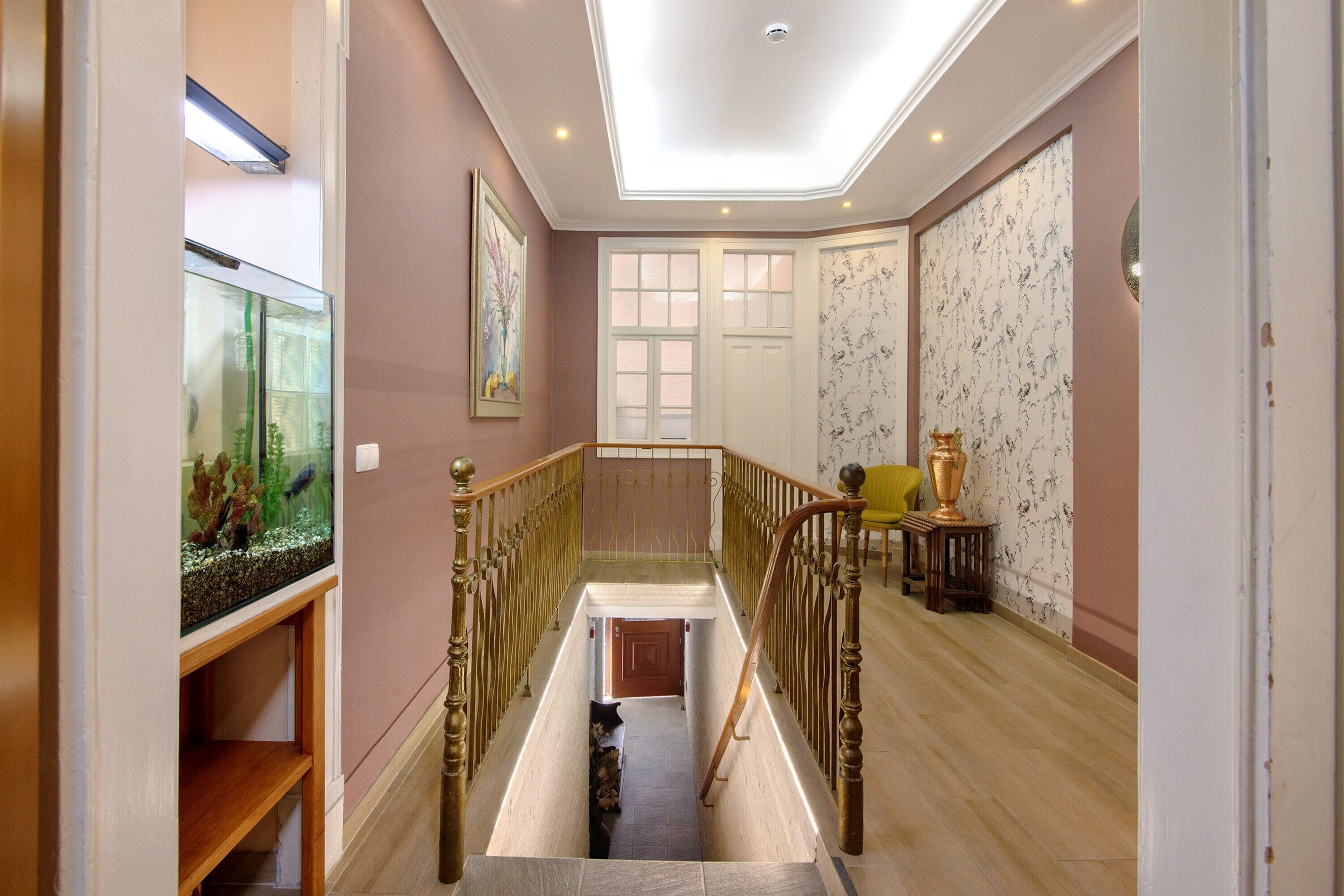 Un couloir avec un escalier, un aquarium, une porte et un mur décoré de motifs.