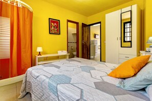 Ein Schlafzimmer mit Bett, Nachttisch, Spiegel und Kleiderschrank.