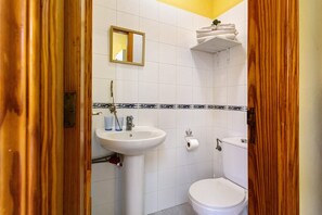 Ein Badezimmer mit Waschbecken, Toilette, Spiegel und Handtuchhalter.