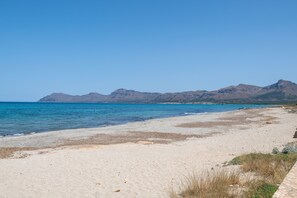 A beach with clear blue water, sandy shore, and mountains in the background. - Holiday Home 'Casa Olivera De Farrutx' with Sea View, Private Pool and Wi-Fi (Son Serra de Marina)