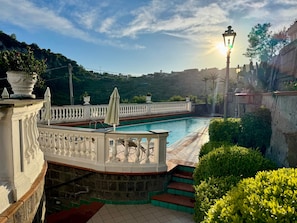 A pool area with a white balustrade, steps leading to the pool, and a lamp post.
