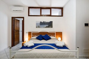 Une chambre à coucher avec un lit, deux lampes de chevet, un tableau au mur et un appareil de climatisation.
