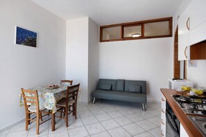 Une cuisine compacte comprenant un coin repas, un canapé et une petite fenêtre.