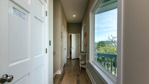 A hallway with white doors, a wooden floor, and a window with a view of trees. - Tequila Sunset:Amazing Dog Friendly Home;Ocean Views/Private Dock; Minutes to Beach;Elevator/WiFi (Edisto Island)