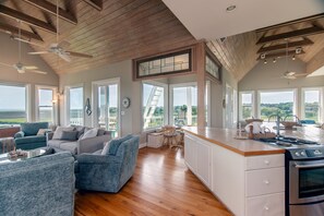 A spacious living area with a kitchen, large windows, and a balcony. - Tequila Sunset:Amazing Dog Friendly Home;Ocean Views/Private Dock; Minutes to Beach;Elevator/WiFi (Edisto Island)