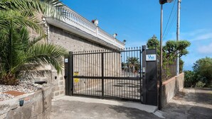 A gated entrance to a building with a stone facade, a metal gate, and a street lamp.