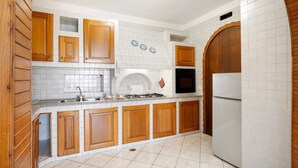 A kitchen with wooden cabinets, a white tiled backsplash, a stove, and a refrigerator.