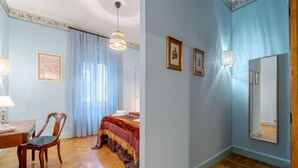 A bedroom with a bed, a chair, a table, and a mirror. - GuestHost - Torino Old Fashion Apartment with Balcony (Torino)