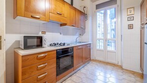 A kitchen with wooden cabinets, a microwave, a stove, and a sink. - GuestHost - Torino Old Fashion Apartment with Balcony (Torino)