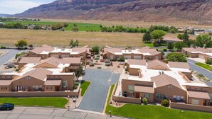 A residential area with modern houses, a central road, and a mountainous backdrop. - Moab Rim Village 2BR condo w/ pool & red rock view (Moab)