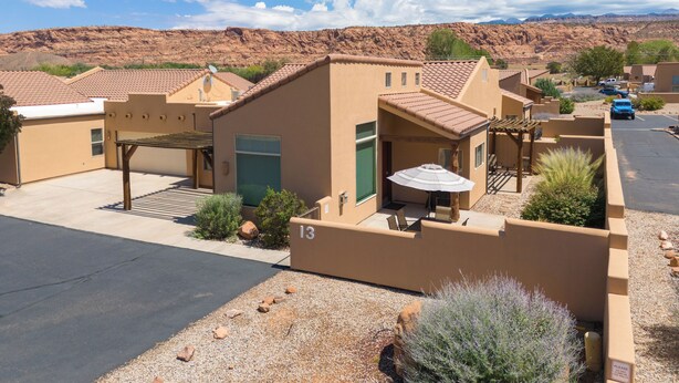 A residential area with houses featuring a uniform architectural style, a paved driveway, and a clear view of the surrounding desert landscape. - Moab Rim Village 2BR condo w/ pool & red rock view (Moab)