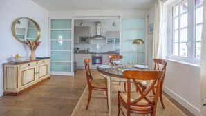 Une cuisine moderne avec un coin repas, comprenant une table ronde en verre, des chaises en bois et un meuble avec un miroir.
