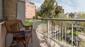 A balcony with wicker chairs, a white railing, and a view of buildings and trees. - GuestHost - 4 Winds Holiday Rental (Roma)