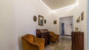 A hallway with two armchairs, a wooden dresser, and a mirror on the wall. - GuestHost - 4 Winds Holiday Rental (Roma)