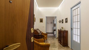 A hallway with a wooden door, a set of yellow armchairs, a wooden cabinet, and a blue door. - GuestHost - 4 Winds Holiday Rental (Roma)