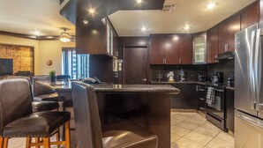 A modern kitchen with dark wood cabinets, stainless steel appliances, and a bar area with leather seating. - Las Palomas Phase I Rubi 901 Exceptional OceanView 3BR 3BA Unit (Puerto Peñasco)