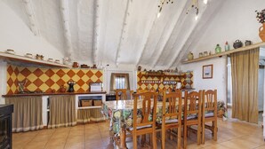 Un comedor con mesa y sillas, una cocina con salpicadero de azulejos y un techo rústico.