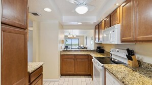 A kitchen with wooden cabinets, granite countertops, a microwave, stove, and a dishwasher.