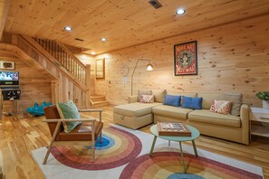 Un interior de madera con una escalera, un sofá modular, una mesa de centro y un televisor.